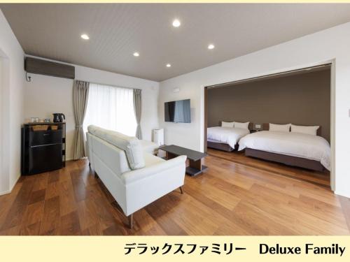 a bedroom with two beds and a couch and a television at Wright Style ANNEX in Naoshima