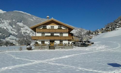 a large building in the snow with mountains in the background at Jogglerhof in Ramsau im Zillertal