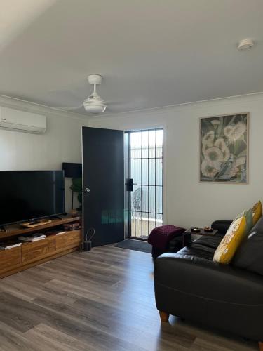 a living room with a black couch and a flat screen tv at Morros Place in Hay