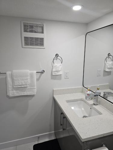 a white bathroom with a sink and a mirror at Contemporary Two Bedroom Basement Suite in Edmonton