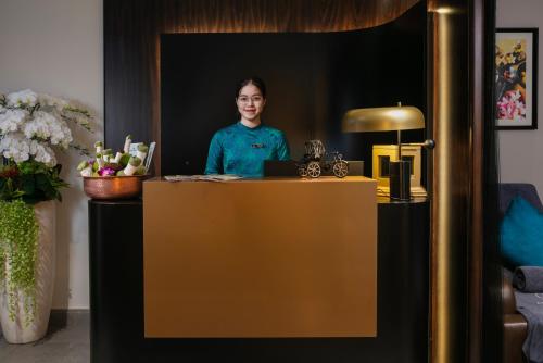 a woman is standing behind a desk in a room at Le Premier Hotel & Rooftop Bar in Hanoi
