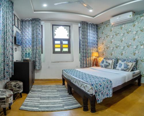 a bedroom with a bed with blue curtains and a window at Haveli Palace - 2BHK Luxury Apartment in Udaipur
