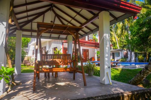 a wooden pergola with two wooden chairs under it at Villa A.SMS in Induruwa