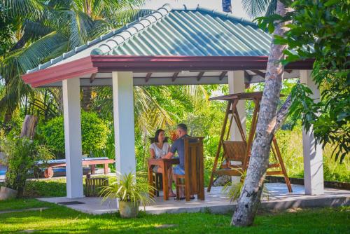a couple sitting at a table in a gazebo at Villa A.SMS in Induruwa
