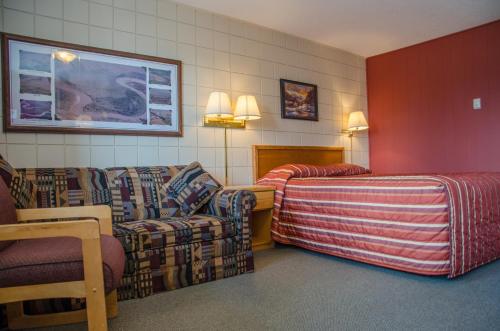 Habitación de hotel con sofá, cama y sillas en Plains Motel, en Brooks