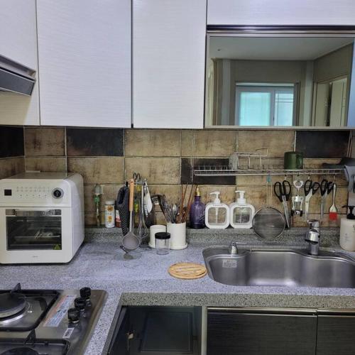 a kitchen counter with a sink and a microwave at Incheon Sungeuidong happy stay for 10 pax in Incheon