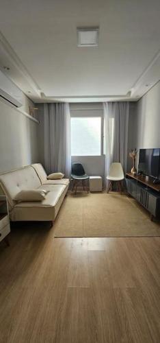 a living room with a couch and a television at Vila Caiçara Apê a 40m da Praia in Solemar