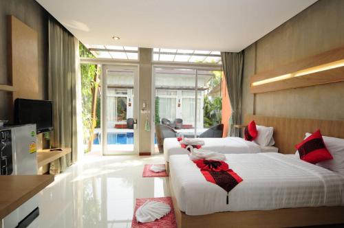 a bedroom with two beds with red bows on them at Phu NaNa Boutique Hotel - SHA Plus in Rawai Beach