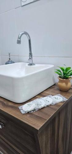a white sink sitting on top of a wooden counter at Vila Caiçara Apê a 40m da Praia in Solemar