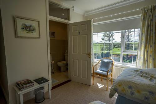 a bedroom with a bed and a window and a chair at Tattykeel House in Omagh