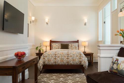 a bedroom with a bed and a flat screen tv at Cheshire Cat Inn & Cottages in Santa Barbara