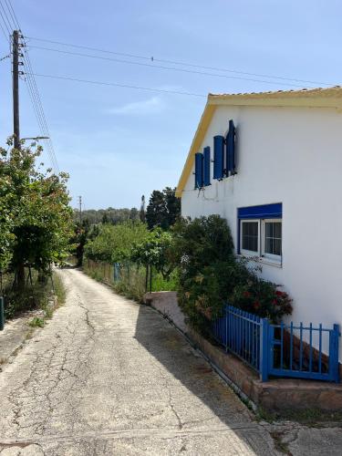a house with a blue fence next to a road at Village Guest House in Corfu