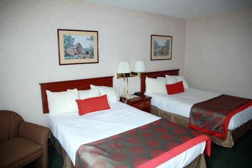 a hotel room with two beds and a chair at Ramada by Wyndham Strasburg Dover in Strasburg
