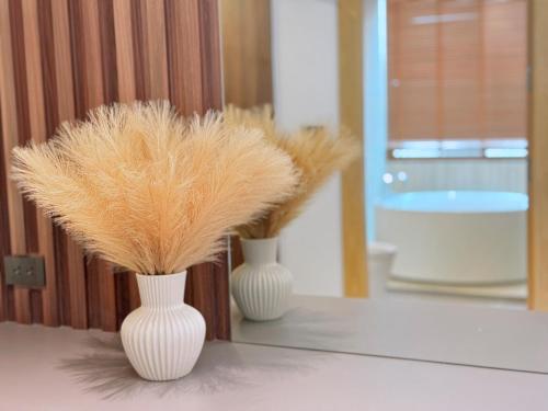 two white vases with feathers in them on a table at PNT LUXURY JOMTIEn in Jomtien Beach
