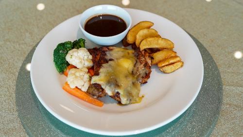 a plate of food with meat and vegetables and a cup of sauce at The Guest Hotel & Spa in Port Dickson