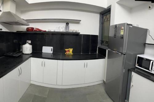 een keuken met witte kasten en een roestvrijstalen koelkast bij 3bhk villa at koramangala in Bangalore
