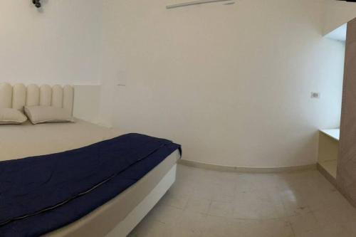 een witte slaapkamer met een bed met een blauwe deken bij 3bhk villa at koramangala in Bangalore