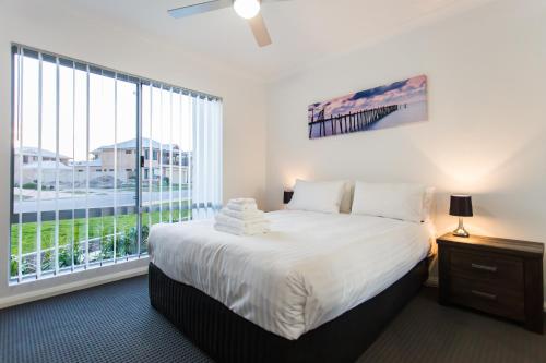a bedroom with a large bed and a large window at Reflections By Rockingham Apartments in Rockingham