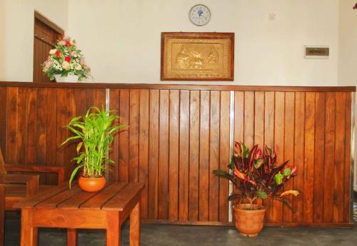 a wooden wall with two potted plants and a table at Seeing Green Udawalawa in Udawalawe