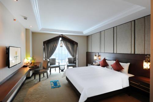 Un dormitorio con una gran cama blanca y una mesa en Al Meroz Hotel Bangkok - The Leading Halal Hotel, en Bangkok
