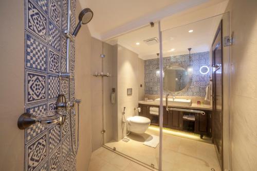 a bathroom with a toilet and a glass shower door at Fragrant Nature Kochi - A Five star Classified Hotel in Cochin