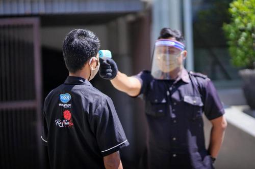 a man wearing a face mask and a police officer at Raffleshom Hotel in Bandung
