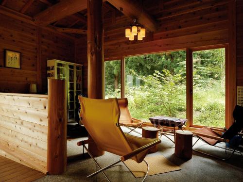 a living room with a yellow chair in a cabin at Rankeisou in Sanjo