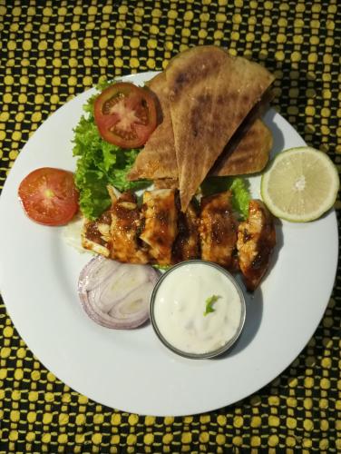 a white plate of food with chicken and other foods at Dishari Tangalle in Tangalle