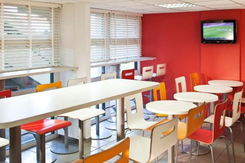 Cette chambre dispose de tables, de chaises et d'une télévision murale. dans l'établissement Premiere Classe Charleville Mezieres, à Charleville-Mézières