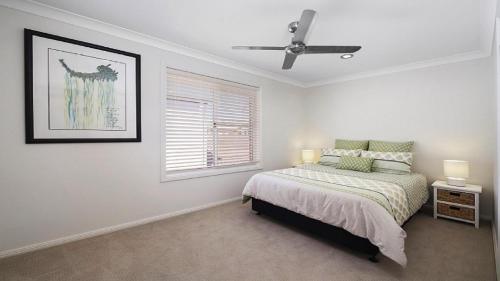 a white bedroom with a bed and a window at Araluen On Henley Accom Property in Terrigal