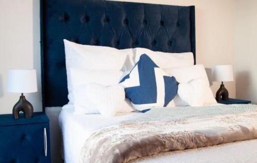 a bed with a blue head board and white pillows at Comfortable lovely apartment in Johannesburg