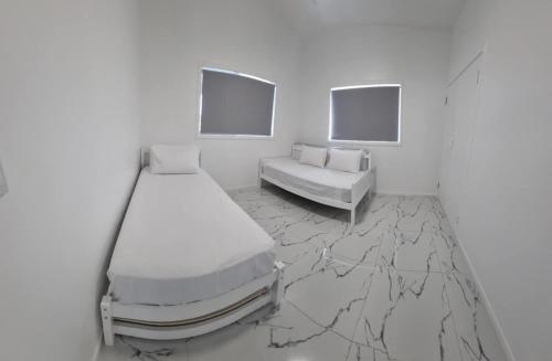 a white room with two beds and a couch at Te Aro Villa in Muri 1 &2 in Rarotonga