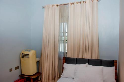 a bedroom with a bed and a window with curtains at Exclusive Villa 24Hr Solar Electricity in Umuahia