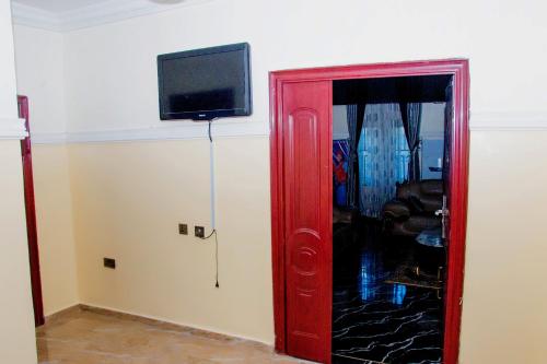 a red door with a television on a wall at Exclusive Villa 24Hr Solar Electricity in Umuahia