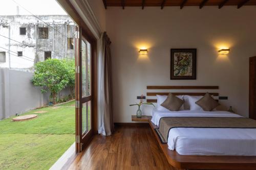 a bedroom with a bed and a large window at Mudliyar House in Hikkaduwa