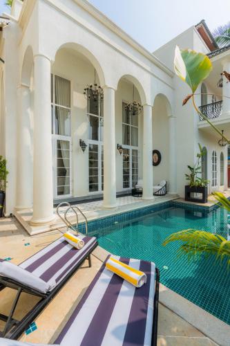 an indoor swimming pool with two lounge chairs next to a house at ELIVAAS 4 BHK Villa with Pvt Pool & Jacuzzi-Yashgeet in Siolim