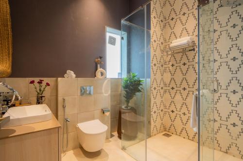 a bathroom with a shower and a toilet and a sink at ELIVAAS 4 BHK Villa with Pvt Pool & Jacuzzi-Yashgeet in Siolim