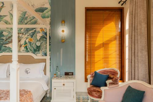 a bedroom with a bed and a chair and a window at ELIVAAS 4 BHK Villa with Pvt Pool & Jacuzzi-Yashgeet in Siolim