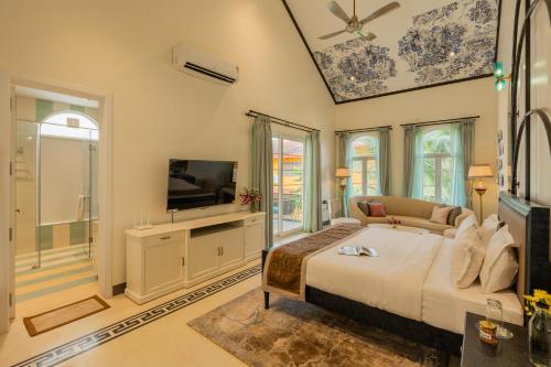 a bedroom with a large bed and a television at ELIVAAS 4 BHK Villa with Pvt Pool & Jacuzzi-Yashgeet in Siolim