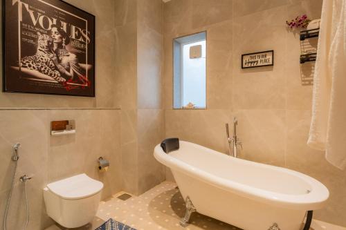 a bathroom with a bath tub and a toilet at ELIVAAS 4 BHK Villa with Pvt Pool & Jacuzzi-Yashgeet in Siolim