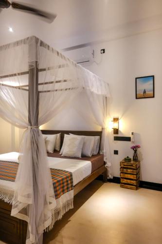 a bedroom with a bed with a canopy at K O C O O N Villa Madiha in Walgama South