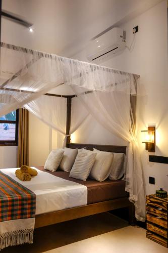 a bedroom with a canopy bed with white curtains at K O C O O N Villa Madiha in Walgama South