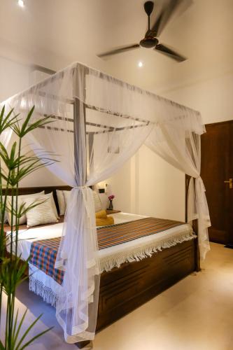 a bedroom with a bed with a canopy at K O C O O N Villa Madiha in Walgama South