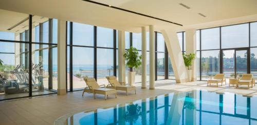 a hotel lobby with a pool and chairs and windows at Maistra Select All Suite Island Hotel Istra in Rovinj