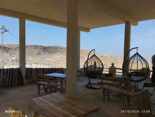 a porch with tables and benches and a view of the desert at Dar Fatma Toujane in Tūjān