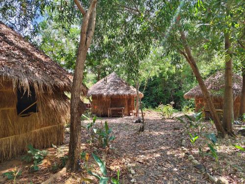 a couple of huts in a forest with trees at Kampot Camping - Eco Retreat in Kampot