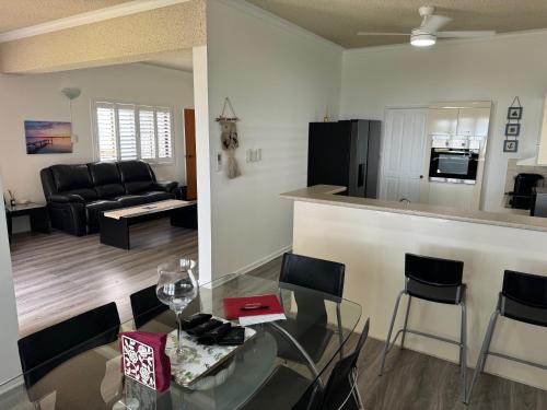 a living room and kitchen with a glass table and chairs at Keith's Place, 1 of the 3 most popular units on Bribie in Bongaree