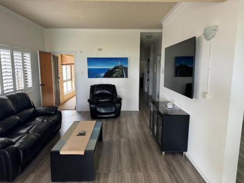 a living room with a leather couch and a chair at Keith's Place, 1 of the 3 most popular units on Bribie in Bongaree