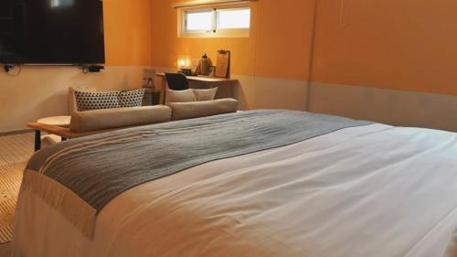 a bedroom with a large bed and a chair at Chill Roof Hotel in Taipei
