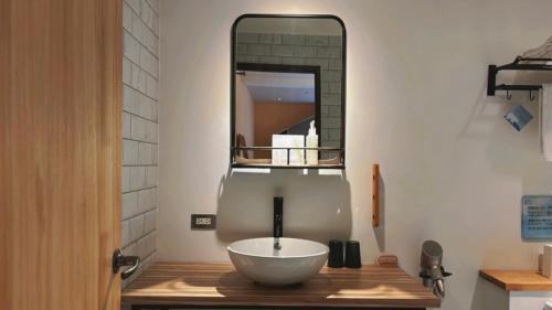 a bathroom with a bowl sink and a mirror at Chill Roof Hotel in Taipei